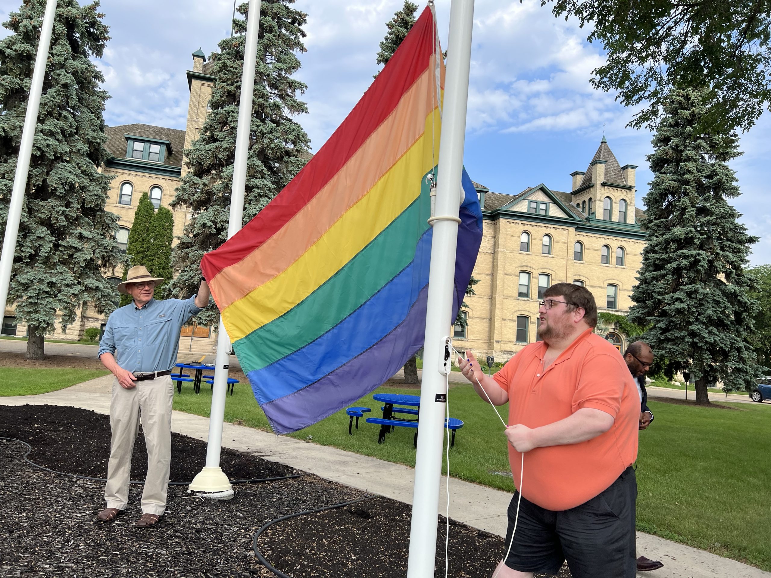 Two people hold a rainbow flag.