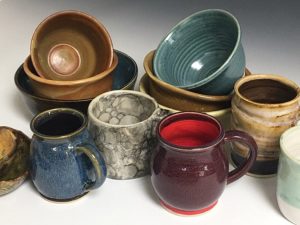 Closeup photo of a large jumbled pile of glazed pottery bowls and mugs.