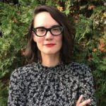 A woman poses in front of foliage