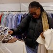 A young woman browses clothing racks while a selection is already draped over her arm.