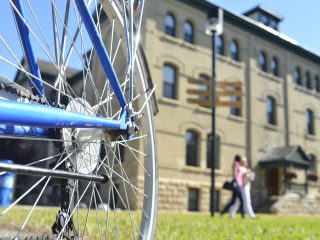 Two students walk along a path behind a locked-up bike.